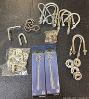 All items laid out: packaged Hillman eye bolts, U-bolts, washers, rollers, quick links, hex keys