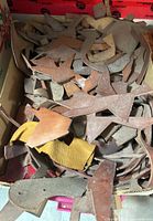 Box filled with assorted leather offcuts in varied colors and shapes