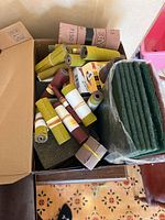 box with multiple sandpaper rolls and stack of green pads