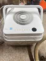 Top view of Midea Cube dehumidifier showing brand logo, fan grill, control panel, stackable design and attached hose