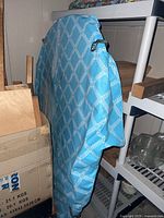 folded round plastic patio table leaning against shelving