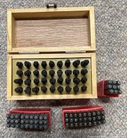 Wooden box opened showing full set of punches, three red-cased punch sets in foreground