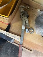 Full view of ratchet cable puller showing handle, hooks, and cable