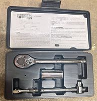 Open case showing ratchet, extension, robotic socket, adapter, and instruction sheet