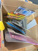 Box containing several packs of 3M and Norton sandpaper with sanding block