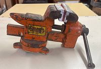Left-side view of orange Smart's bench vise showing jaws, handle and swivel base
