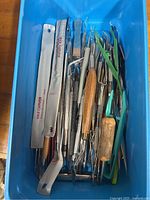 Blue bin filled with assorted stainless steel carving tools, picks, tweezers