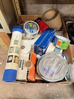 Cardboard box containing assorted tape rolls and packaging