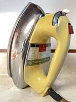 Side view of GE iron showing yellow handle, chrome soleplate, fabric guide label