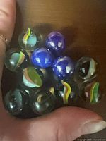 Close-up of 11 marbles in hand, showing colours and patterns