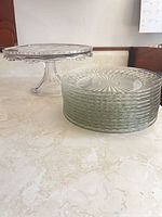 Pressed glass cake stand and stack of Duralex plates on countertop