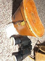 Binoculars with caps, tan leather case, lens cleaner packet