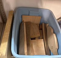 Bin holding multiple assorted wood boards and offcuts