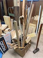Box filled with assorted wood pieces, additional boards leaning around