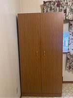 Front view of the wooden wardrobe showing double doors and handles