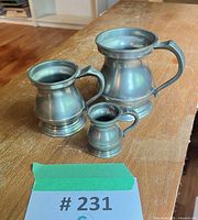 Three graduated pewter pub jugs grouped on table