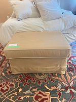 Front view of beige ottoman on patterned rug