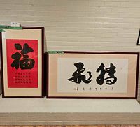 Both framed calligraphy pieces leaned against wall