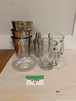 Group view showing glass decanter, two glass pitchers, three nested stainless steel ice buckets, stainless steel cocktail shaker