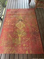 Full view of rectangular red and saffron rug on deck