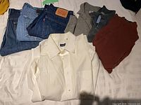 Jeans, sweaters and shirt laid out on bed