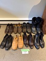 Eight pairs of shoes and boots arranged in two rows on floor