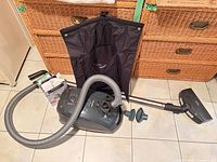 Overall view of vacuum, hose, wand, floor head, accessory bag, green attachments, bag box