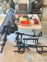 Overview showing folded umbrella, timers, flashlight, landscape lights on table and bike rack on floor