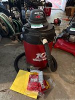 Front view of Shop-Vac 10-gallon vacuum with hose and accessory packaging nearby