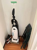 Vacuum, hose, cord, step stool folded, box of bags in corner