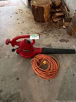 Toro Ultra leaf blower vac with attached nozzle and coiled orange extension cord on floor