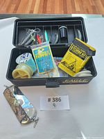 Open Eagle Claw tackle box showing contents: lures, weights, line spools, Fin-Dall Rap lure, Storm Kit booklet