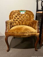 Front view of golden velvet button-tufted armchair