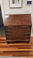 Full view of mahogany secretary desk showing drop front, serpentine drawers and claw feet