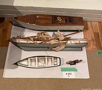 Top view of all four wooden model boats laid out on floor showing size and condition