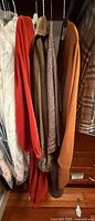 Four garments hanging: red dress, brown velour robe, heather brown dress, burnt-orange dress