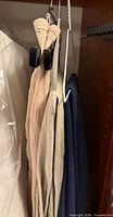 Three garments hanging on clamp and regular hangers: beige, light beige, navy