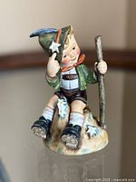 Front view of Goebel Hummel Mountaineer figurine showing boy seated on rock with walking stick