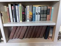 Entire bookshelf showing encyclopedias on lower shelf and assorted titles above
