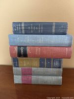 Stack of six cloth hardcover books showing spine titles and condition
