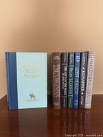 Front cover of Around the World in 80 Days alongside seven spined hardcovers