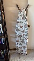 Front view of the standing ironing board showing floral cover and metal legs