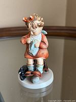 Front view of figurine showing girl on stool knitting with cat at base