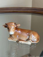 Front left view of porcelain ox figurine on glass surface