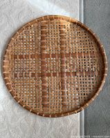 Front view of round woven rattan tray showing lattice weave and raised rim
