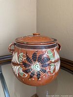 Front view of redware bean pot showing hand-painted design and side handles