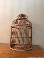 Full view of cylindrical wooden birdcage on tabletop