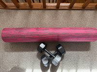 Yoga mat rolled beside pair of hex dumbbells