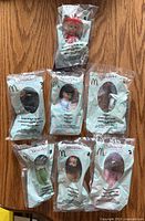 Front view of seven sealed Wizard of Oz dolls in numbered McDonald’s bags