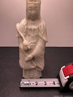 Front view of carved Guanyin statue with tape measure for scale